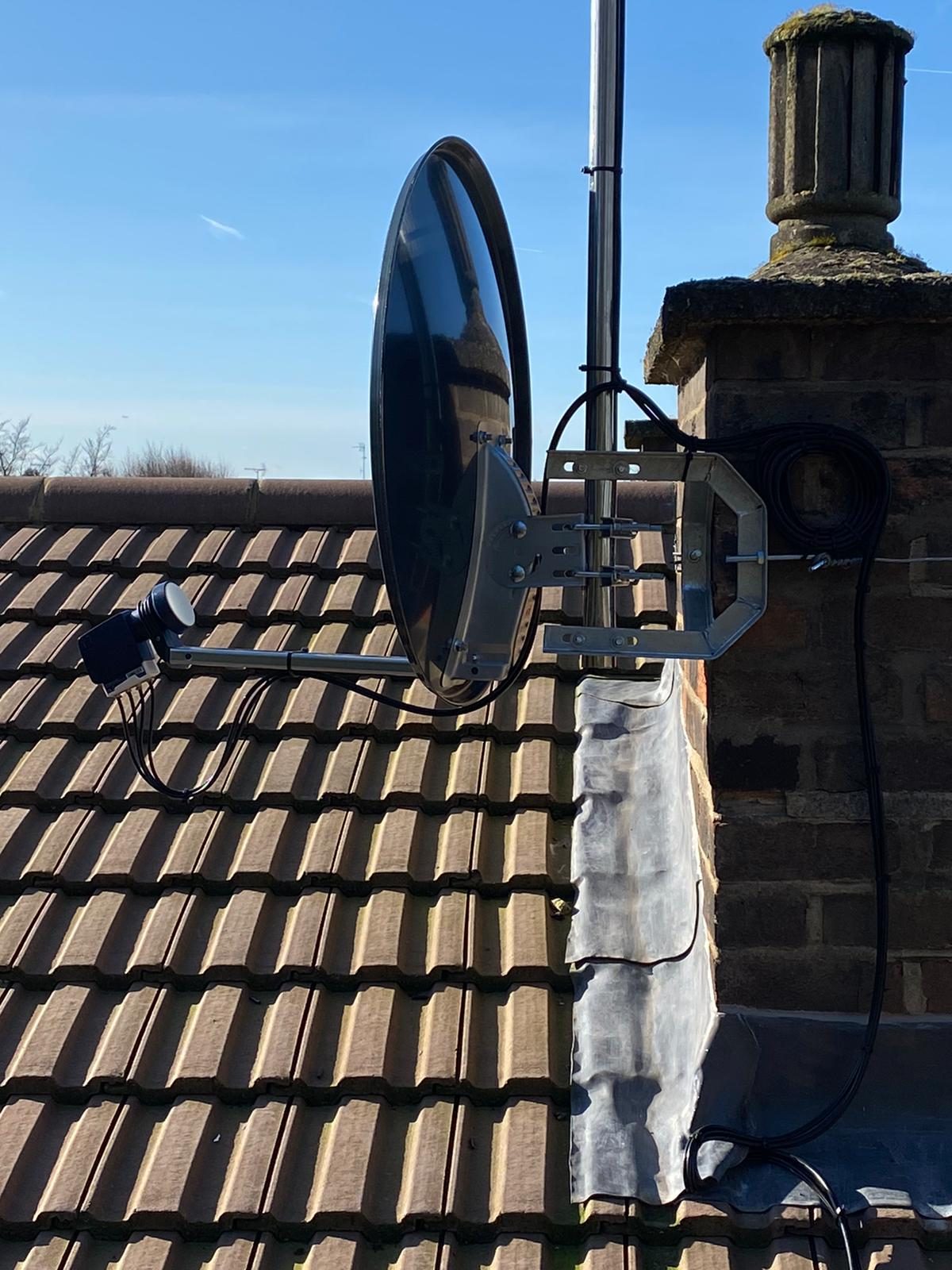Satellite dish and LNB installed on a roof, cabled to a chimney stack